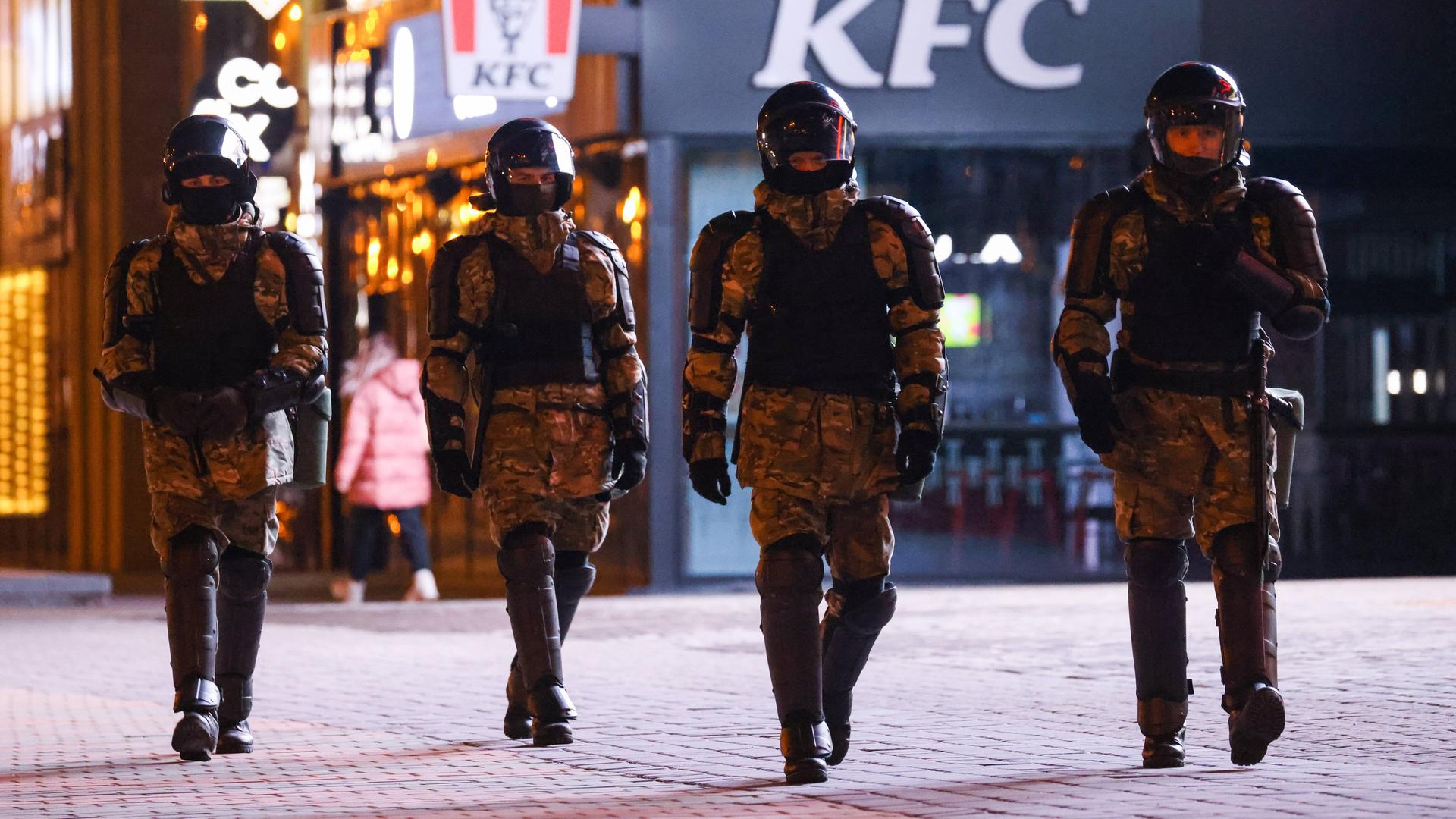 Vier gepanzerte Polizisten mit Helm laufen durch Minsk.