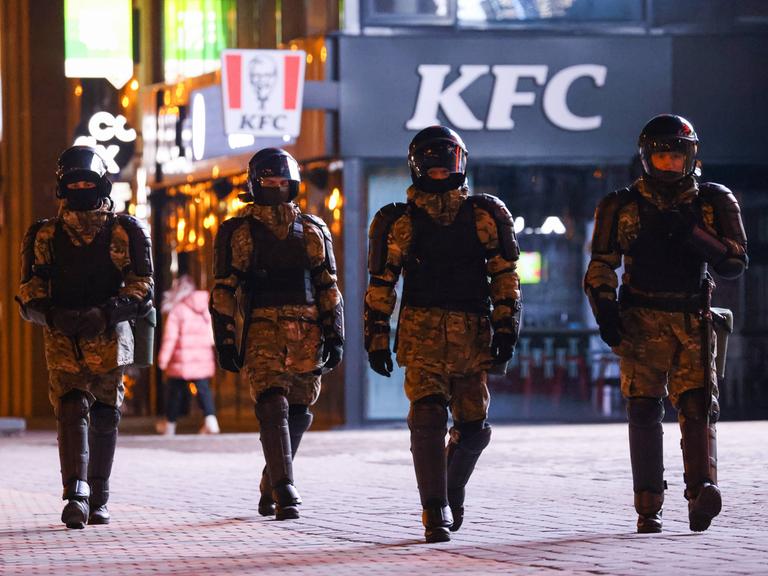 Vier gepanzerte Polizisten mit Helm laufen durch Minsk.