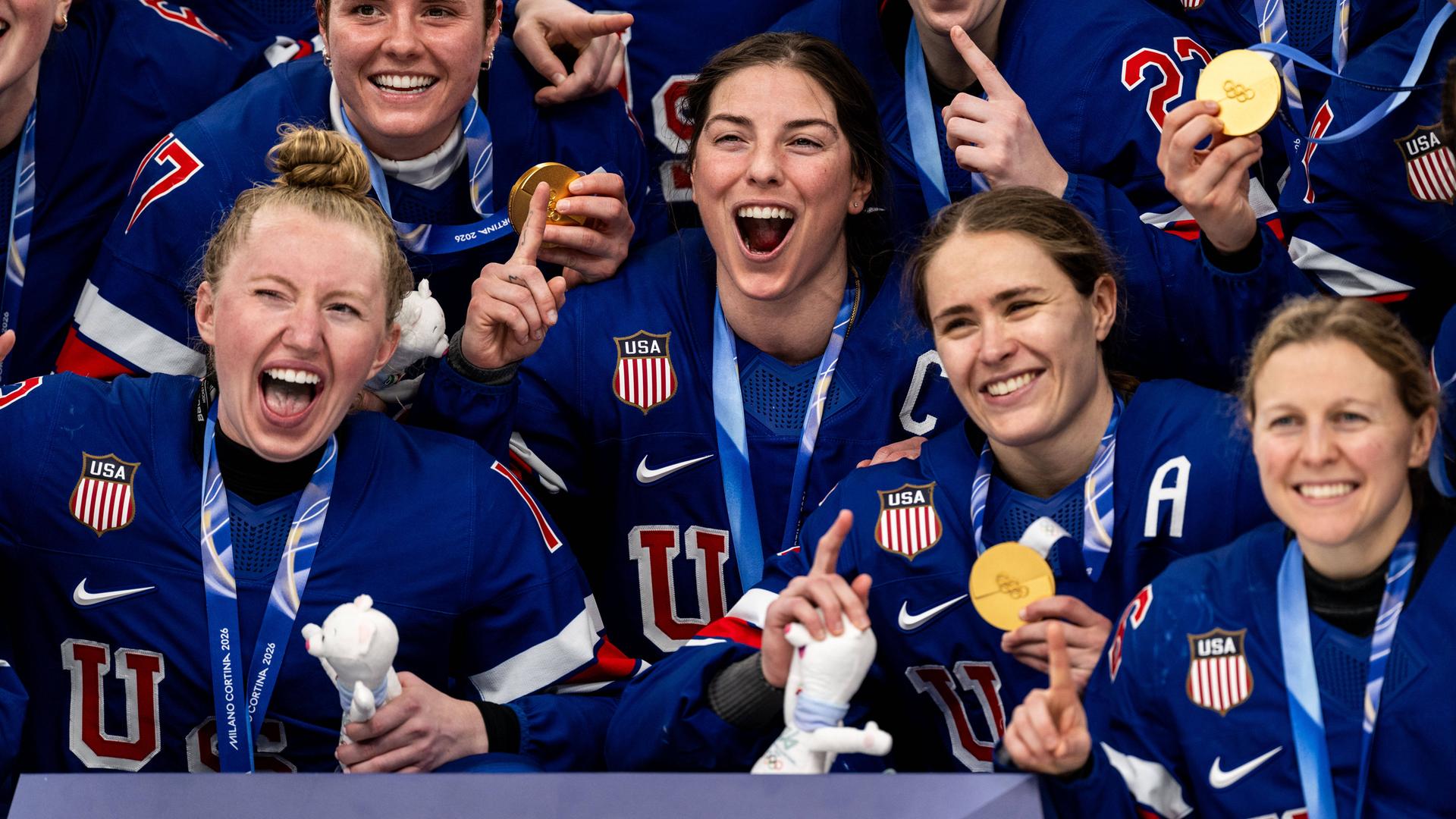 US-Eishockeyspielerinnen jubeln und halten ihre Olympia-Goldmedaillen in die Kamera.