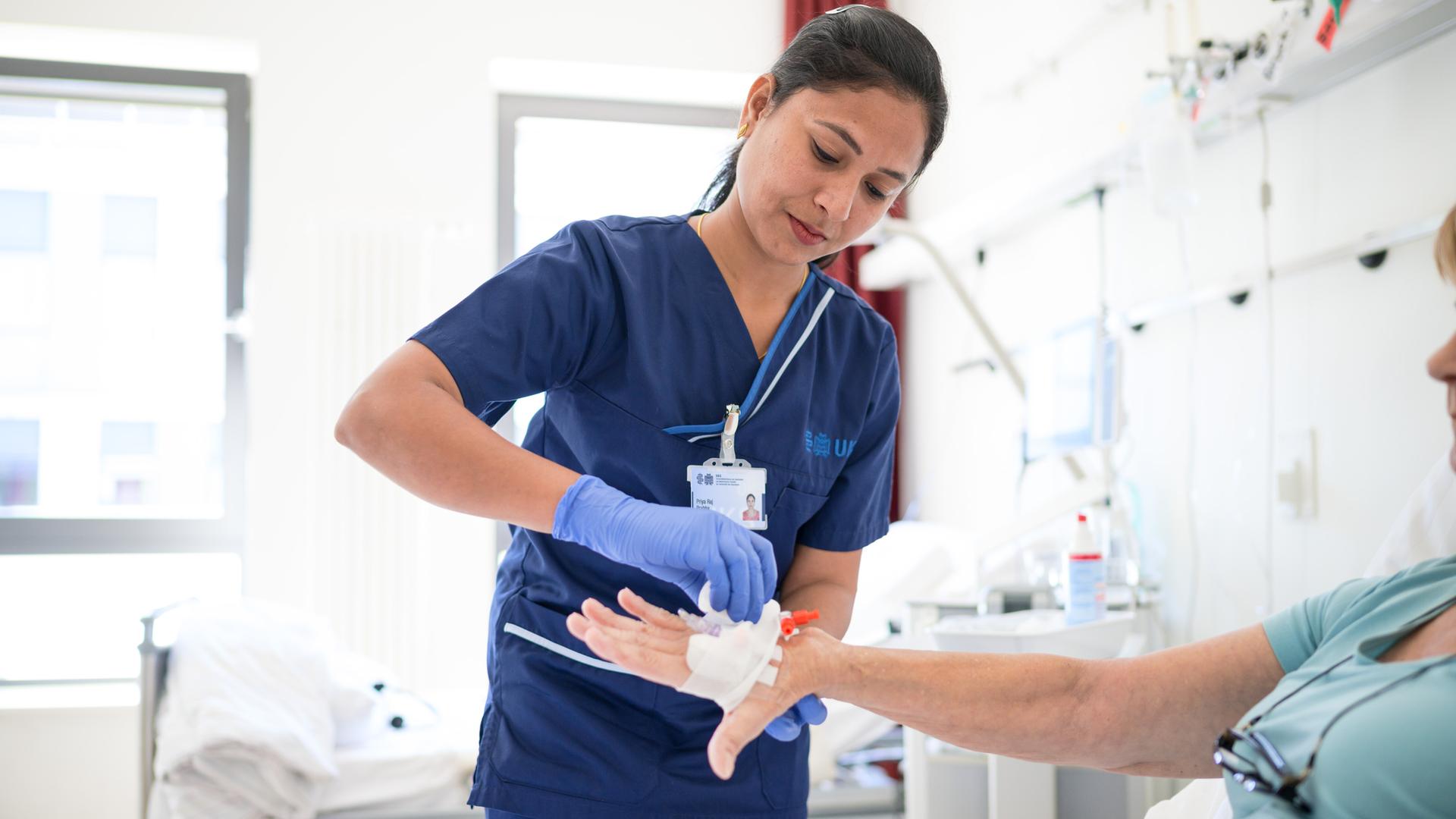 Die indische Pflegekraft Priyaraj Prabha legt einer Patientin eine Infusion. 