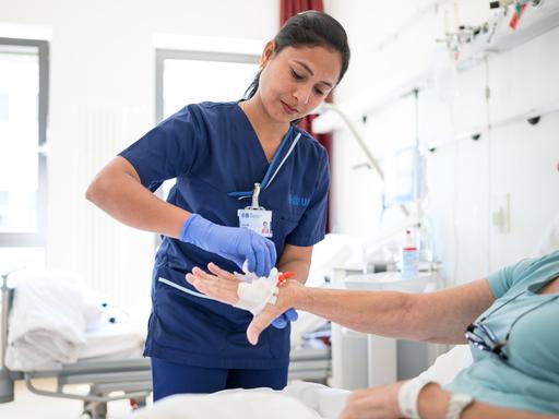 Die indische Pflegekraft Priyaraj Prabha legt einer Patientin eine Infusion. 