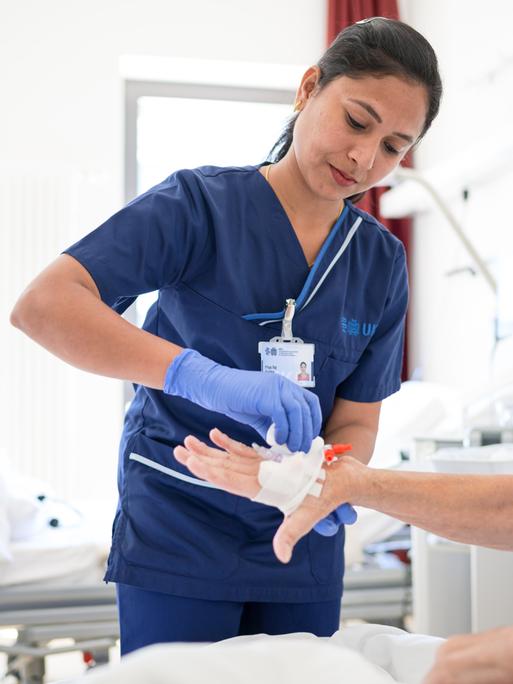 Die indische Pflegekraft Priyaraj Prabha legt einer Patientin eine Infusion. 