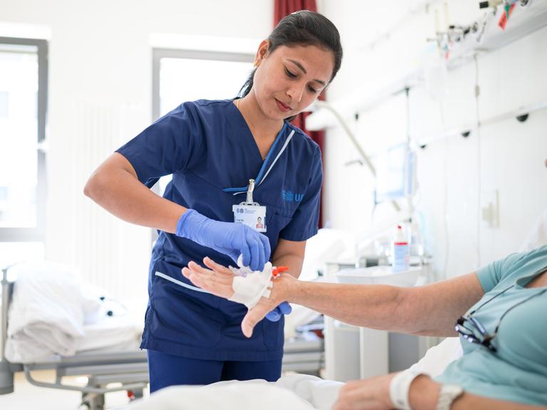 Die indische Pflegekraft Priyaraj Prabha legt einer Patientin eine Infusion. 