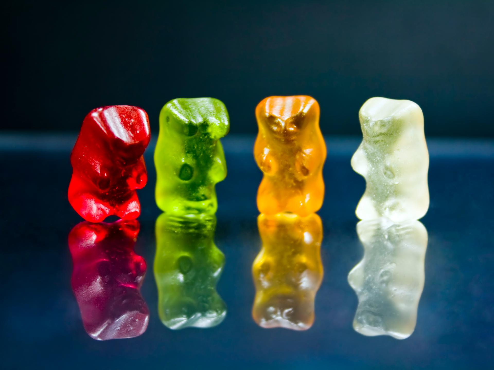 Vier bunte Gummibärchen vor schwarzem Hintergrund