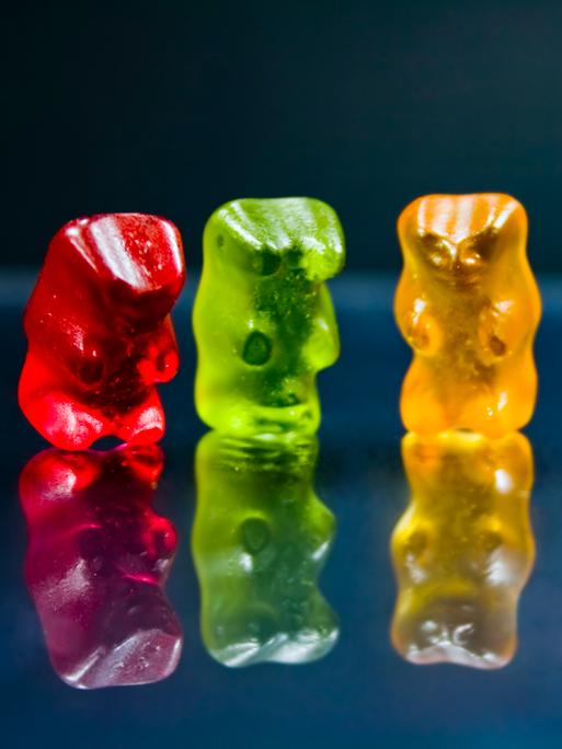 Vier bunte Gummibärchen vor schwarzem Hintergrund Vier bunte Gummibärchen vor schwarzem Hintergrund
