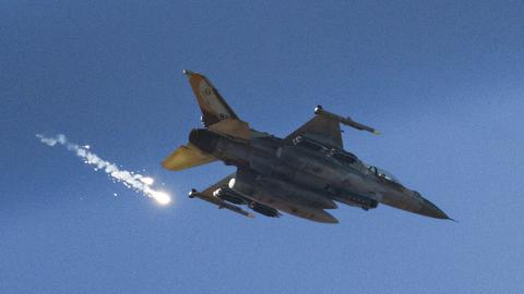 Man sieht den Kampfjet von unten vor einem wolkenlosen blauen Himmel. Daneben der Rauchstreifen der abgeschossenen Rakete.