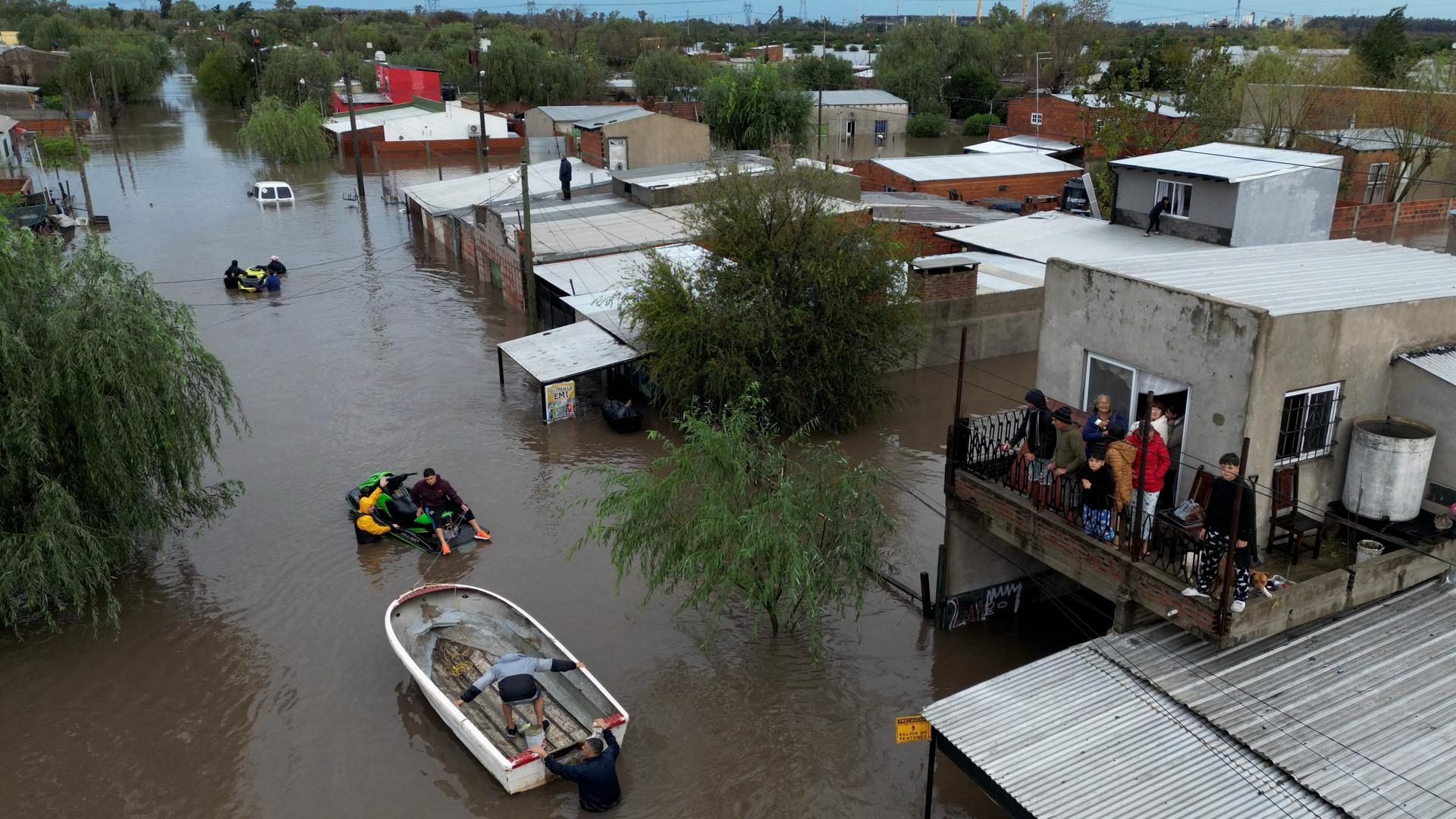 Straßen in einem Ort stehen unter Wasser. Auf dem Wasser ist ein Schlauchboot mit mehreren Menschen unterwegs. Straßen in einem Ort stehen unter Wasser. Auf dem Wasser ist ein Schlauchboot mit mehreren Menschen unterwegs.