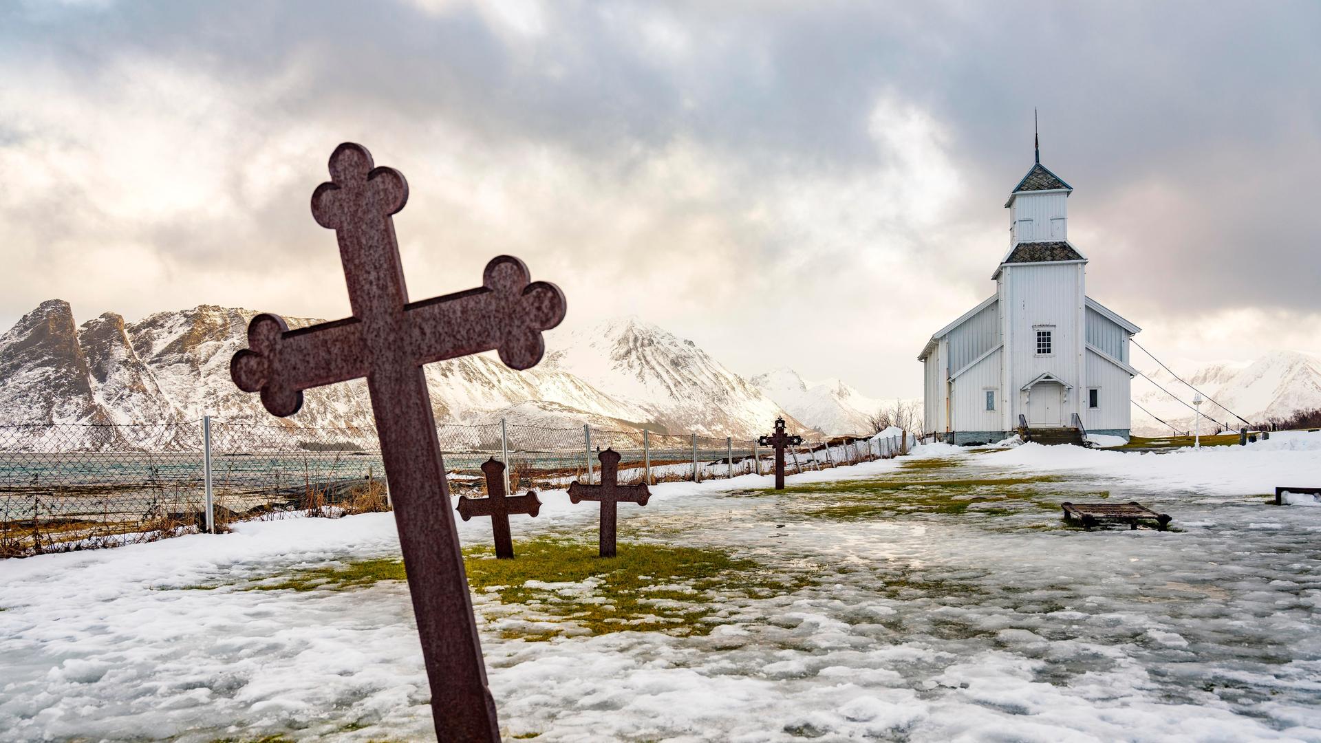 Gimsøy Kirche mit Friedhof, hinten schneebedeckte Berge, Winter, Gimsøya, Lofoten, Norwegen, Europa