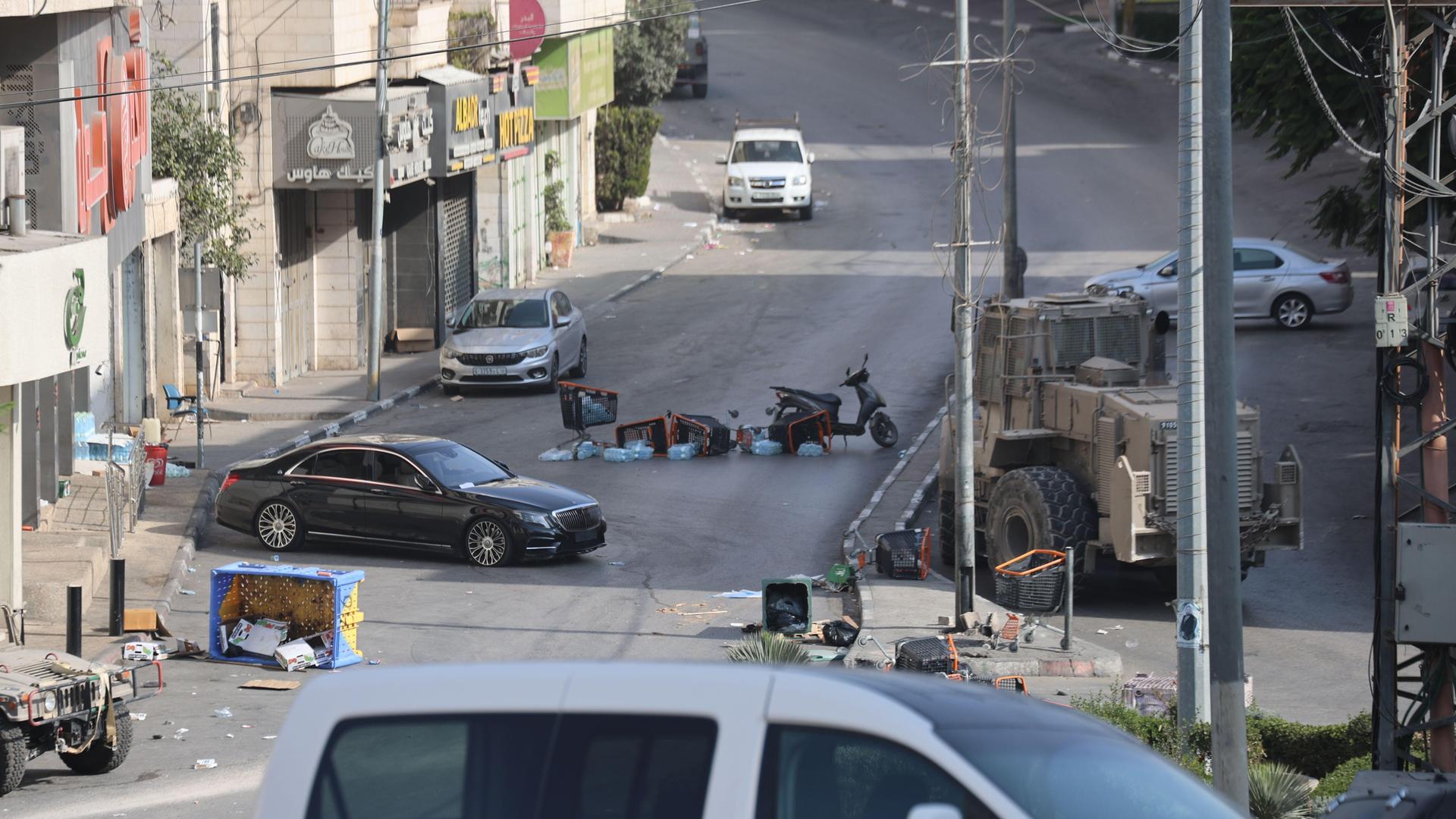 Kisten und ein Mopeds liegen umgekippt auf einer verlassenen Straße in Hebron.