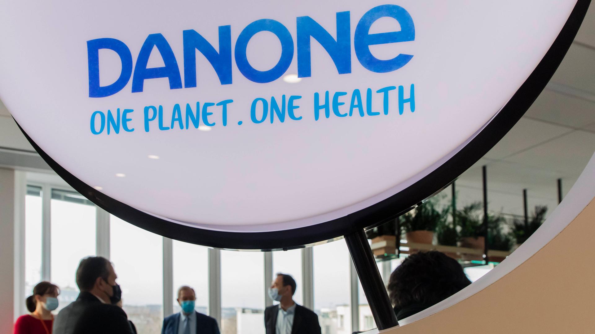Einige Herren mit Mundschutz unterhalten sich im Schatten einer riesigen Danone-Werbe-Installation. Einige Herren mit Mundschutz unterhalten sich im Schatten einer riesigen Danone-Werbe-Installation.