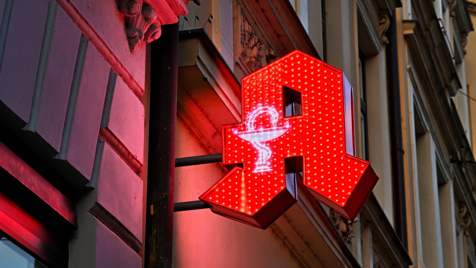 An einer Fassade prangt rot beleuchtet das Hinweisschild für Apotheken.