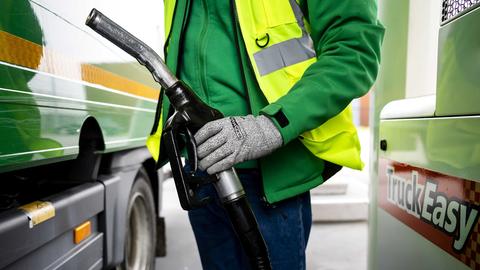 Ein Lkw-Fahrer tankt Diesel an einer Zapfsäule. 