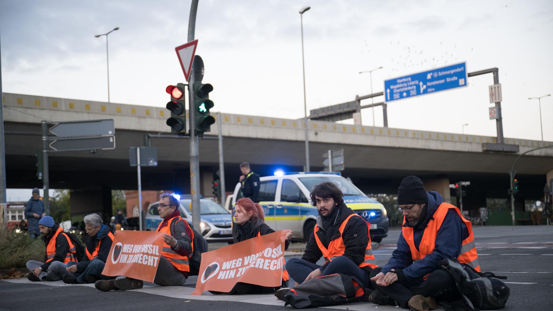 Aktivisten kleben während einer Straßenblockade der Klimaschutzaktivisten "Letzte Generation" auf der Straße einer Autobahnabfahrt in Berlin.