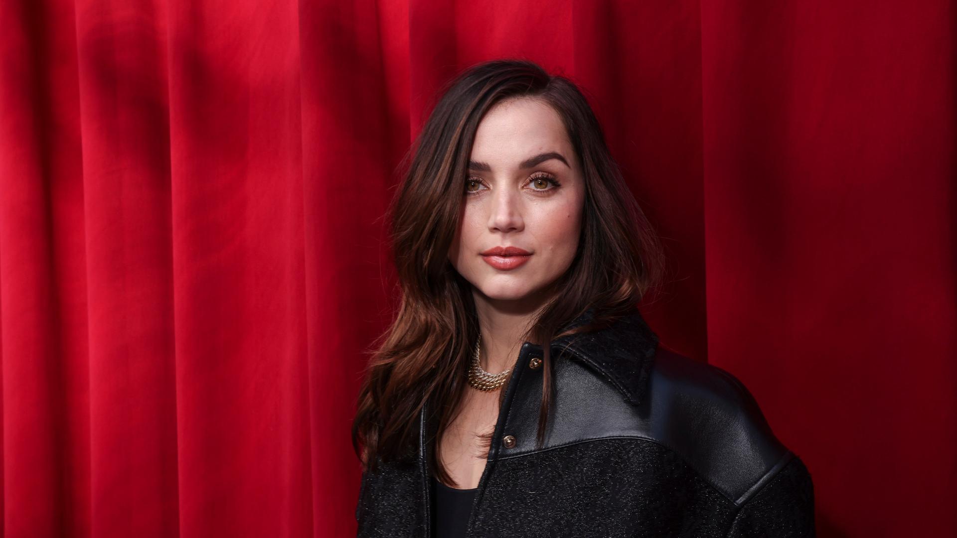Die Schauspielerin Ana de Armas steht vor einem roten Vorhang. Die Schauspielerin Ana de Armas steht vor einem roten Vorhang.