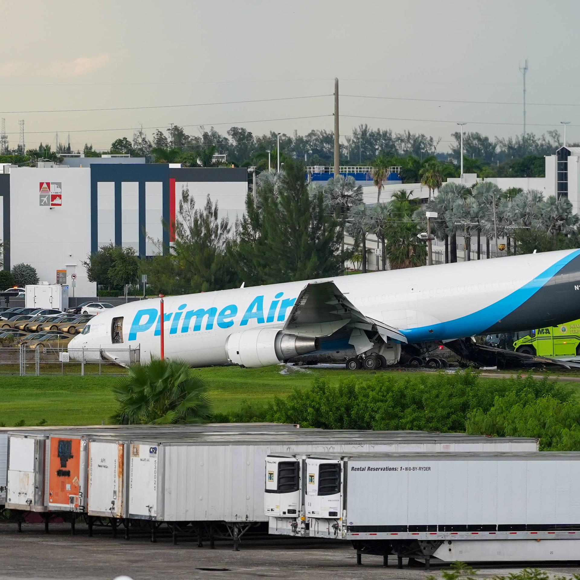 Ein Flugzeug mit der Aufschrift "Prime Air" liegt am Unfallort am Miami International Airport. Zwei Einsatzfahrzeuge stehen daneben.