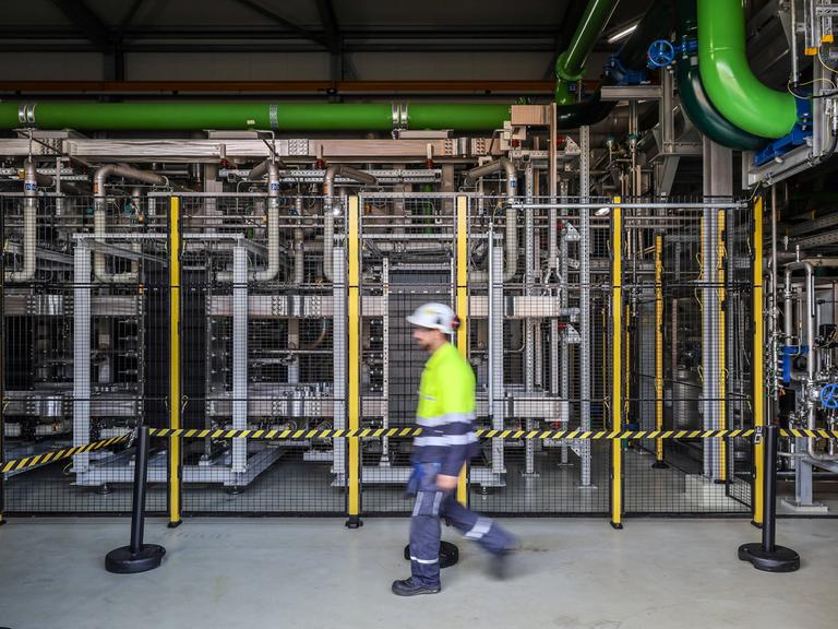 Ein Mann mit Schutzhelm läuft durch eine Wasserstofffabrik