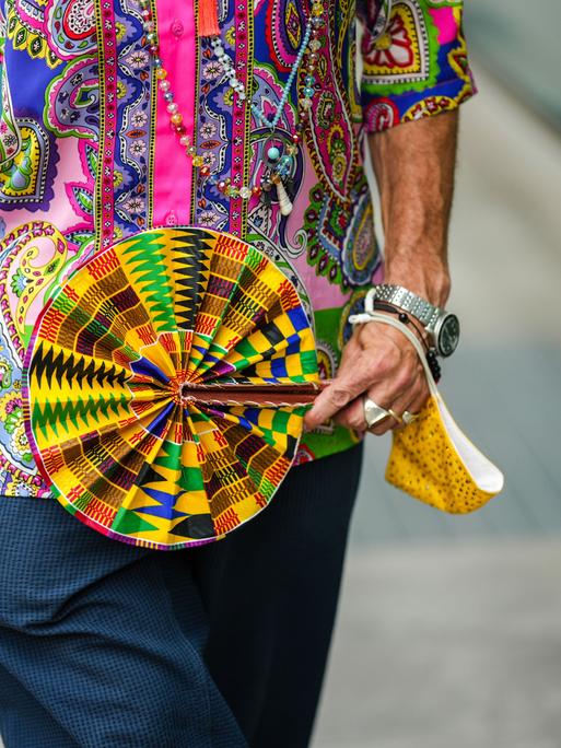 Street Style: Ein Mann mit buntem Fächer auf der Fashion Week in Mailand, 2022.