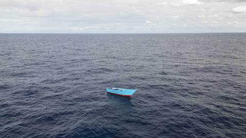 Ein leeres blaues Boot inmitten des dunklen Mittelmeeres.