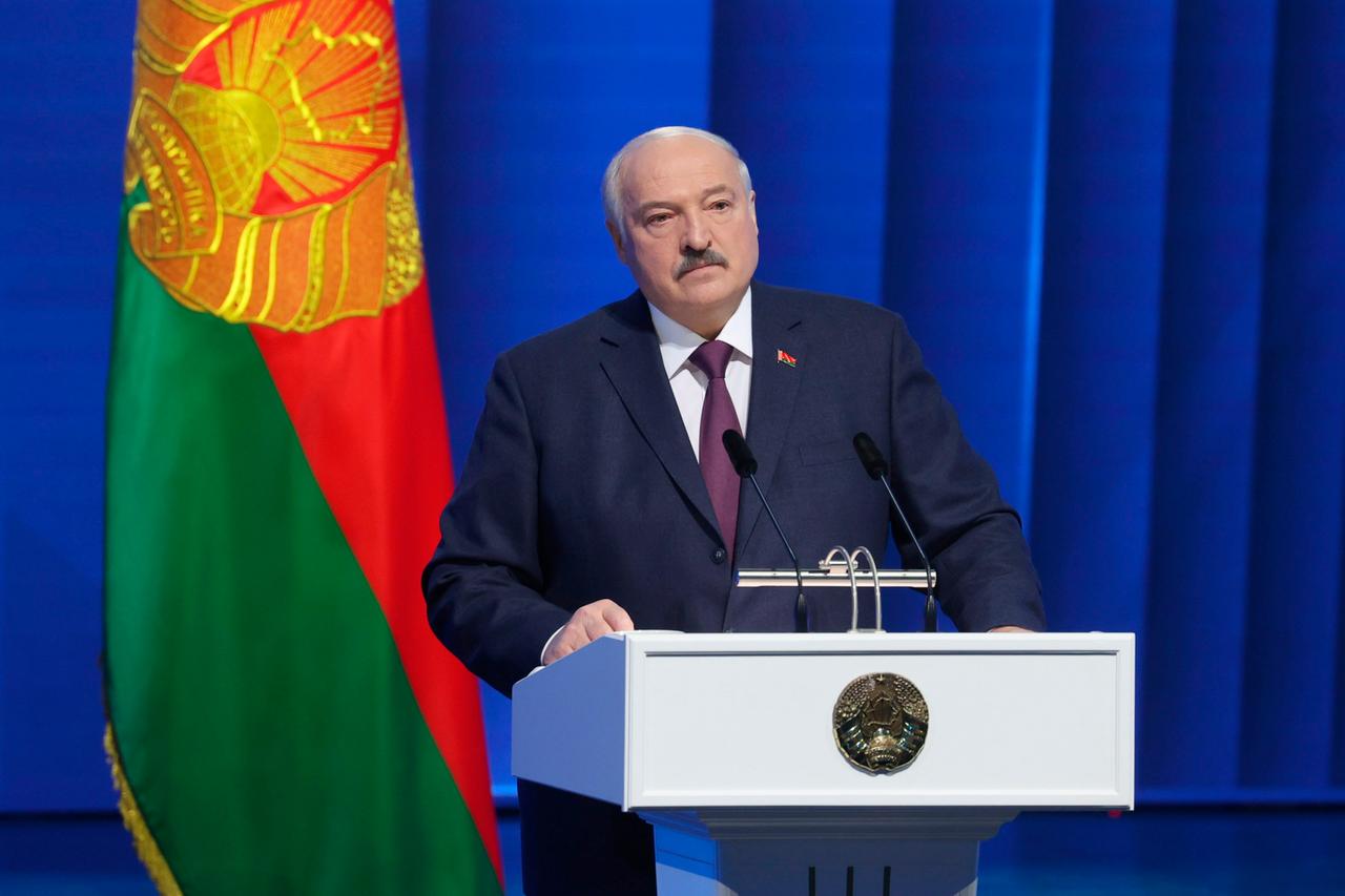 Der belarussische Präsident Lukaschenko steht hinter einem Rednerpult. Hinter ihm ein blauer Vorhang und die belarussische Fahne.