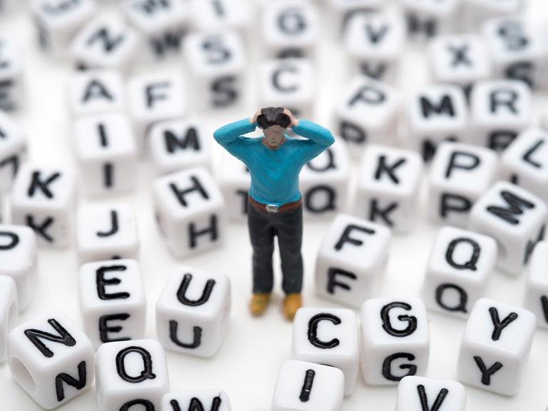 Illustration: Die Figur eines verzweifelten Mannes steht zwischen verschiedenen Buchstaben.