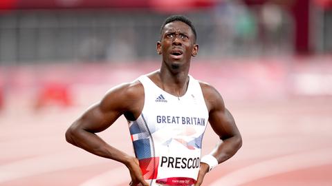 Ein Sprinter im Trikot von Großbritannien steht auf der Laufbahn, die Hände in den Hüften, und schaut nach oben.