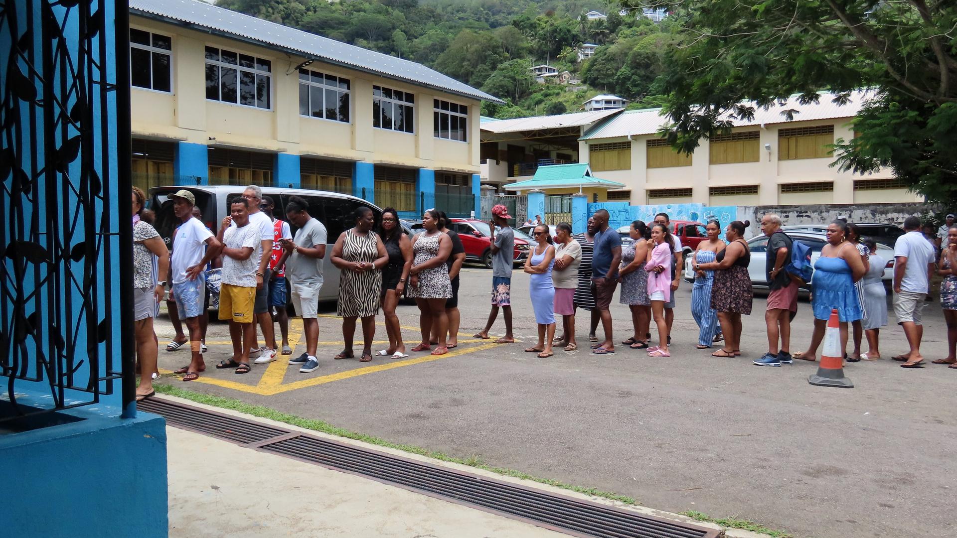 Menschen auf den Seychellen stehen vor einem Wahllokal, um ihre Stimme
        abzugeben. 