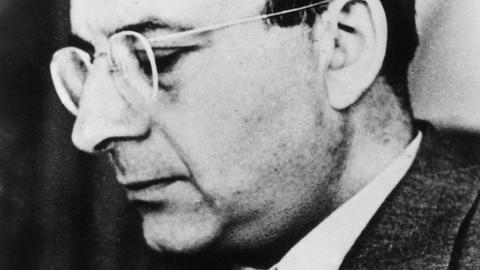 Schwarz-weiße Seitenaufnahme von Erich Fromm mit Brille und im Anzug.