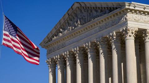 Eine US-Flagge weht im Wind vor dem Gebäude des Supreme Court in Washington mit der Inschrift "Equal justice under law".