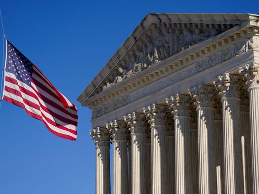 Eine US-Flagge weht im Wind vor dem Gebäude des Supreme Court in Washington mit der Inschrift "Equal justice under law".
