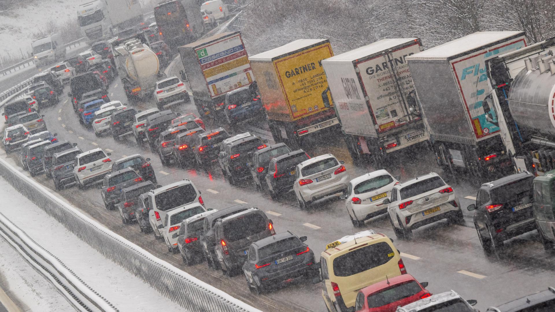 PKW, Busse und LKW stehen auf einer Autobahn im Stau.