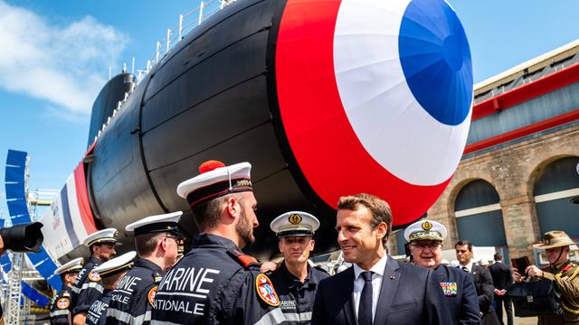 Der französische Präsident Macron spricht mit einem Mitarbeiter der Marine. Im Hintergrund steht ein U-Boot.
