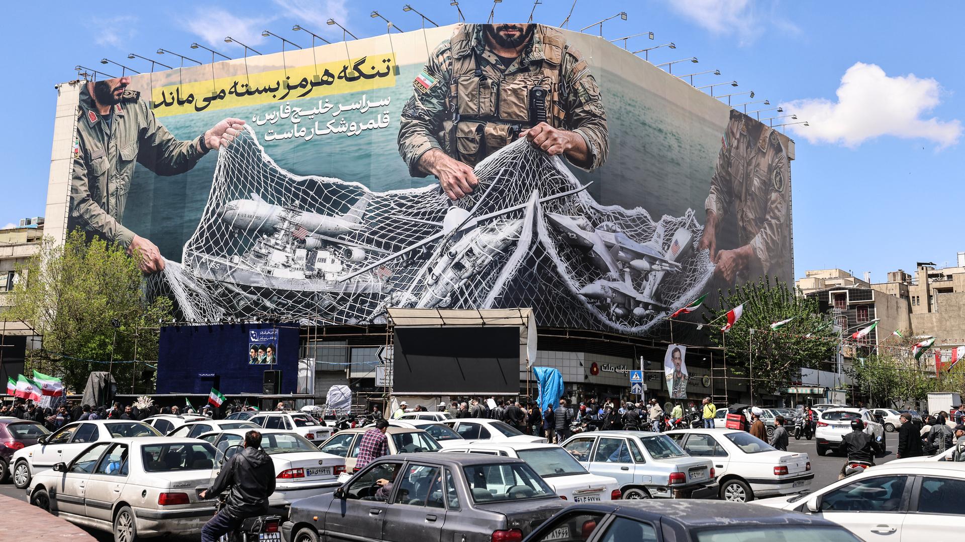 Ein iranisches Propagandaplakat zeigt Soldaten, die ein Fischernetz voller Schiffe zusammenziehen.