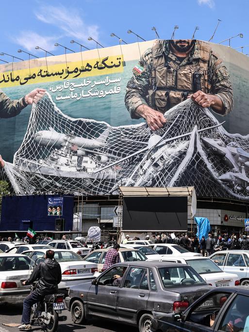 Ein iranisches Propagandaplakat zeigt Soldaten, die ein Fischernetz voller Schiffe zusammenziehen.