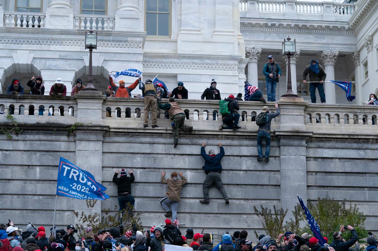 Etliche Männer klettern die Wand vor dem Kapitol hoch