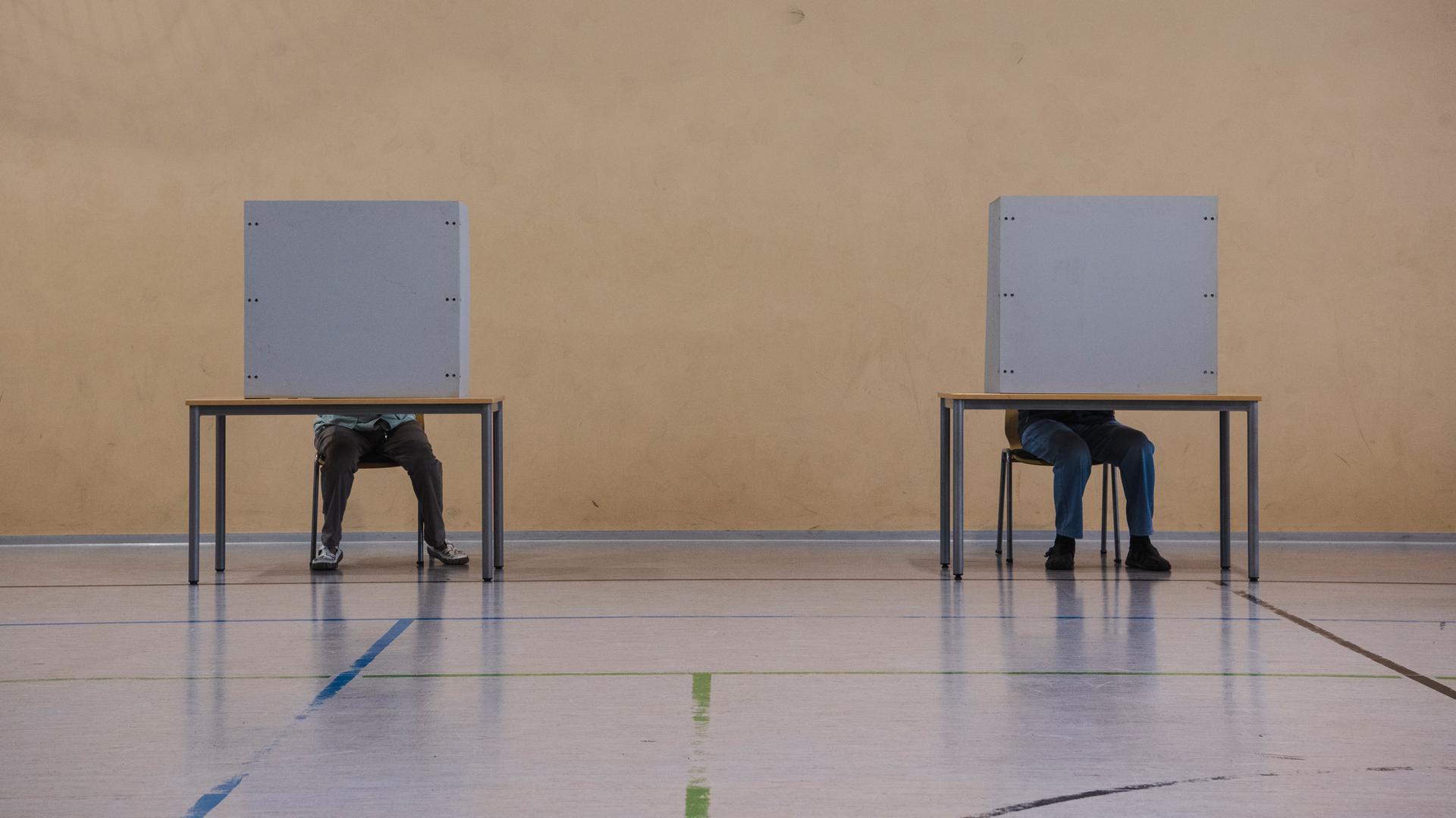 Eine Frau und ein Mann geben ihre Stimme bei der Oberbürgermeisterwahl in Cottbus im Wahllokal ab.