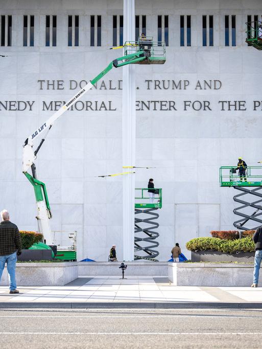 Arbeiter haben den neuen Schriftzug am Kennedy Center in Washington DC angebracht. Auf dem Bild sind noch vier Hebebühnen zu sehen.