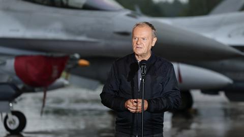 Donald Tusk spricht am 11.9.2025 bei einem Treffen mit polnischen F-16-Piloten, im Hintergrund ist ein Kampfjet zu sehen.