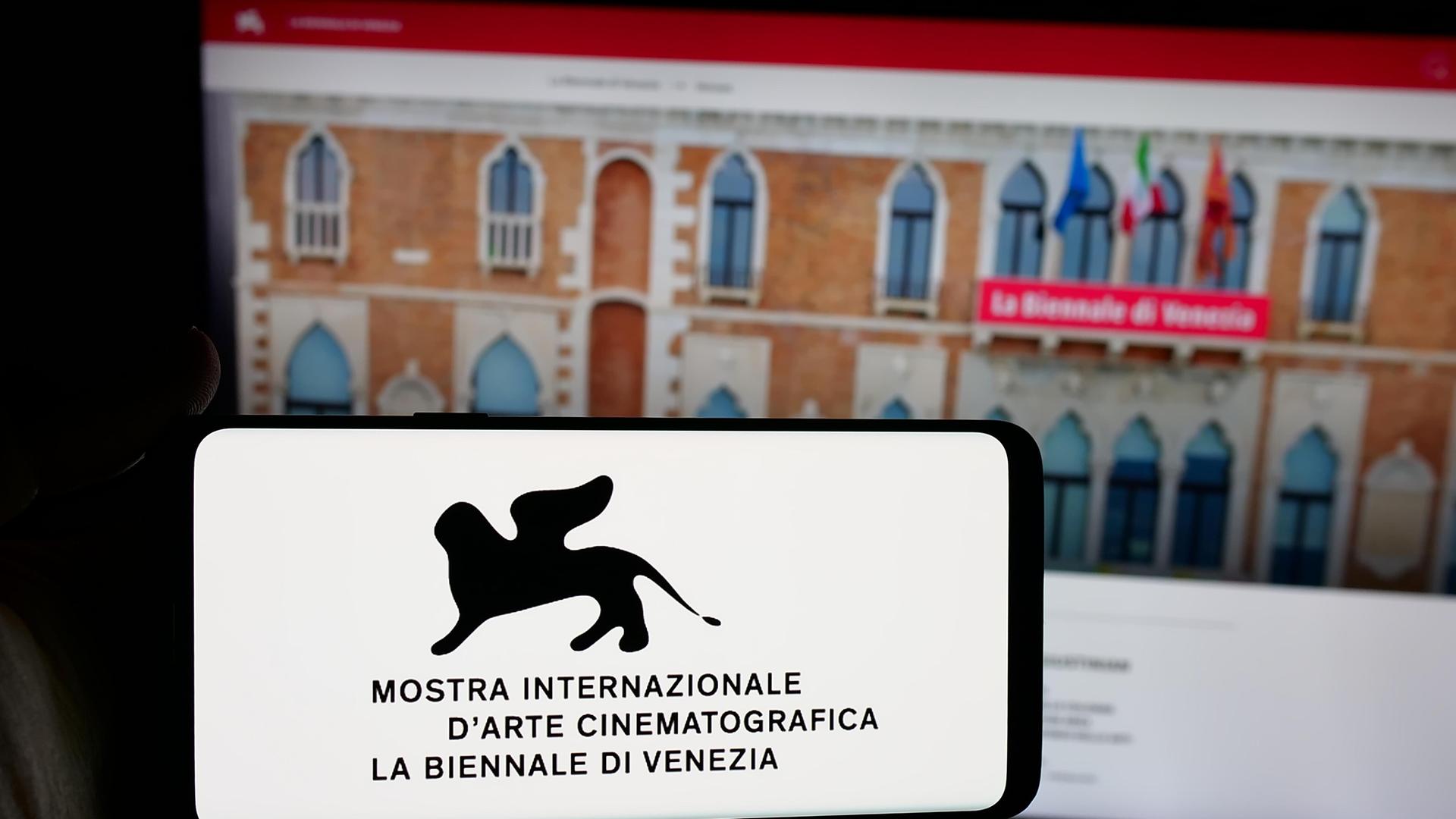Auf dieser Fotoillustration hält eine Person ein Smartphone in der Hand, auf dessen Bildschirm das Logo der Filmfestspiele von Venedig (Biennale) vor einer Website zu sehen ist.
Auf dieser Fotoillustration hält eine Person ein Smartphone in der Hand, auf dessen Bildschirm das Logo der Filmfestspiele von Venedig (Biennale) vor einer Website zu sehen ist.