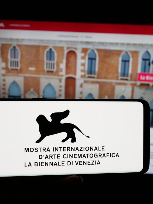 Auf dieser Fotoillustration hält eine Person ein Smartphone in der Hand, auf dessen Bildschirm das Logo der Filmfestspiele von Venedig (Biennale) vor einer Website zu sehen ist.
Auf dieser Fotoillustration hält eine Person ein Smartphone in der Hand, auf dessen Bildschirm das Logo der Filmfestspiele von Venedig (Biennale) vor einer Website zu sehen ist.