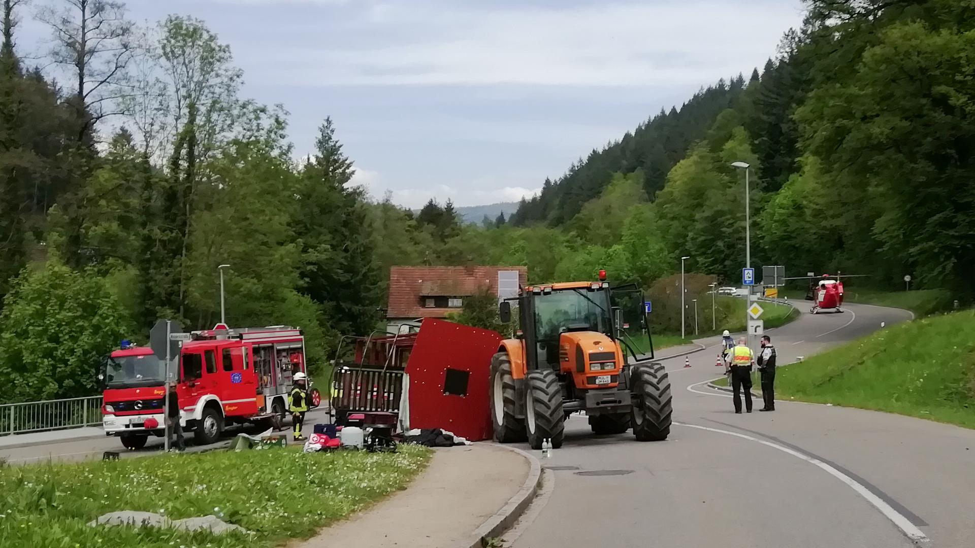 Rettungskräfte stehen nach einem Unfall neben einem einem umgestürzten Maiwagen, der von einem Traktor gezogen wurde. Rettungskräfte stehen nach einem Unfall neben einem einem umgestürzten Maiwagen, der von einem Traktor gezogen wurde.