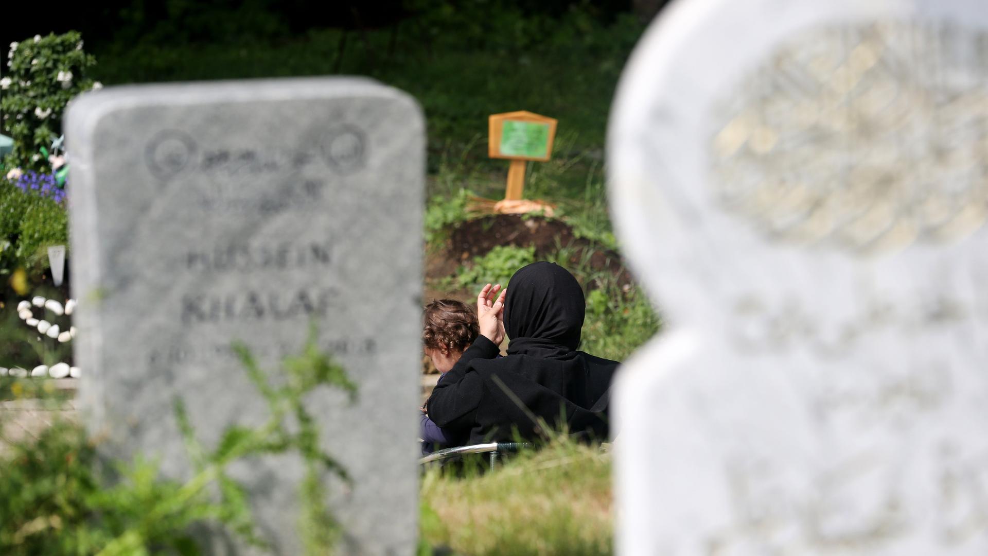 Eine muslimische Mutter und ihre Tochter besuchen ein Grab auf dem islamischen Gräberfeld am Friedhof am Hügel Hallo in Essen.
