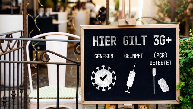 Tafel mit der Aufschrift "Hier gilt 3G+: genesen, geimpft, (PCR) getestet" vor einem Café als Schutzmaßnahme gegen die weitere Verbreitung des Coronavirus