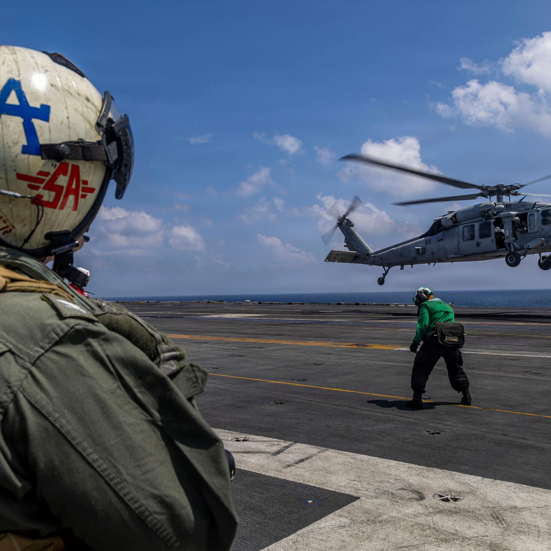 Das Foto zeigt den Kommandanten des  Flugzeugträgers USS Abraham Lincoln von hinten. Im Hintergrund ist ein Hubschrauber zu sehen.