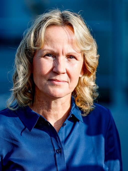 Ein Porträt von Bundesumweltministerin Steffi Lemke (Bündnis90/Die Grünen), blonde Haare, dunkelblaue Bluse vor blauem Hintergrund. 