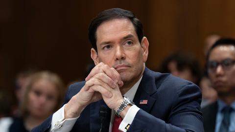 US-Außenminister Marco Rubio schaut nachdenklich und hat seine Hände auf dem Tisch aufgestützt und gefaltet. 
