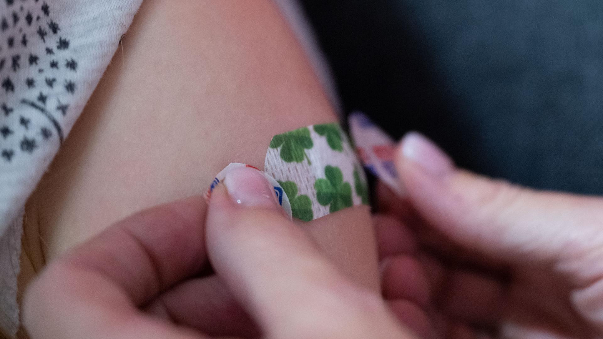 Eine Impfärztin klebt an einem Impfstützpunkt mit dem Titel "Impfpünktchen" der Stadt Heilbronn bei einer Kinderimpfung ein Pflaster auf den Oberarm eines Kindes.