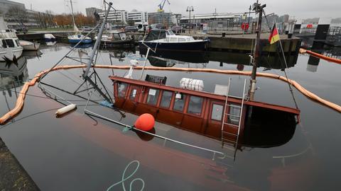 Gesunkener Angelkutter mit deutscher Fahne im Rostocker Stadthafen