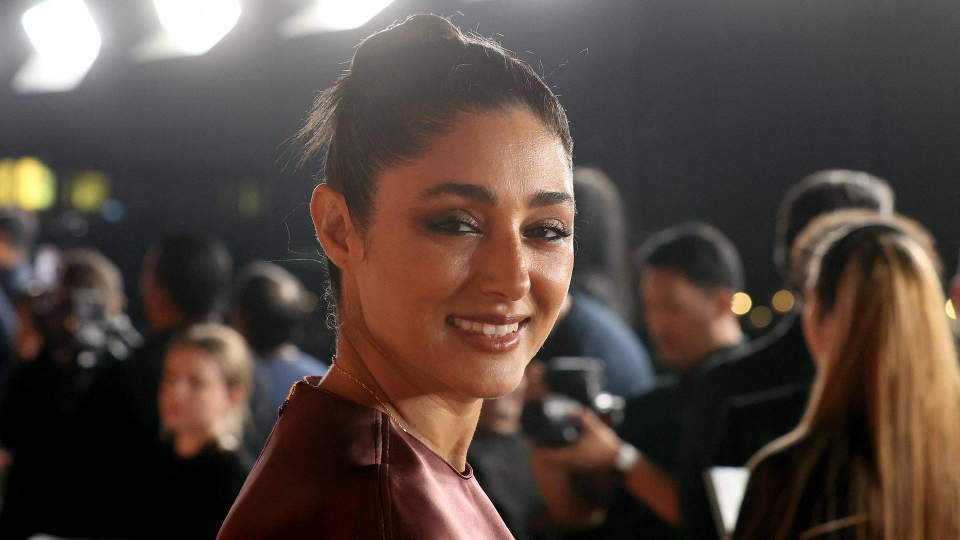 Nahaufnahme vom Kopf der stark geschinkten und lächelnden Farahani. Im Hintergrund weitere Personen.