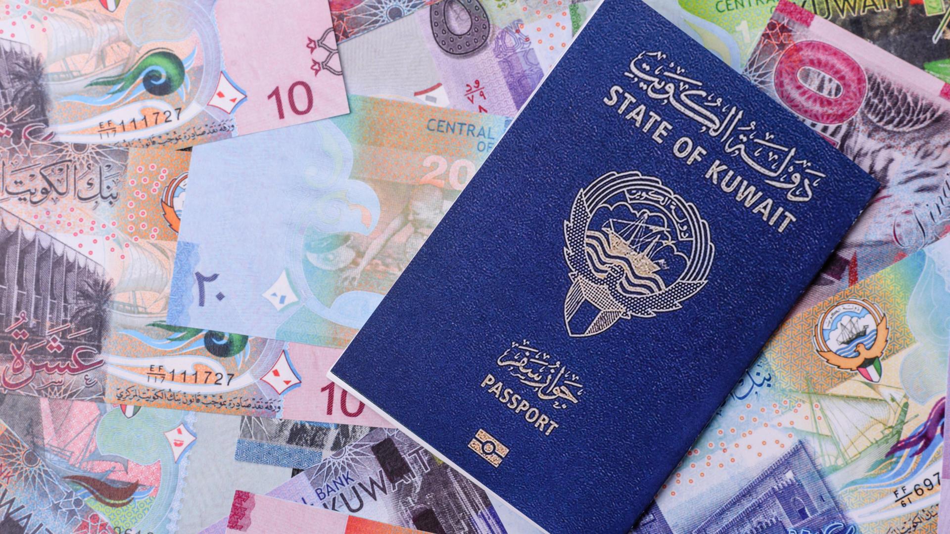 Bildmontage: Der blaue kuwaitischer Reisepass liegt auf vielen Geldscheinen. 