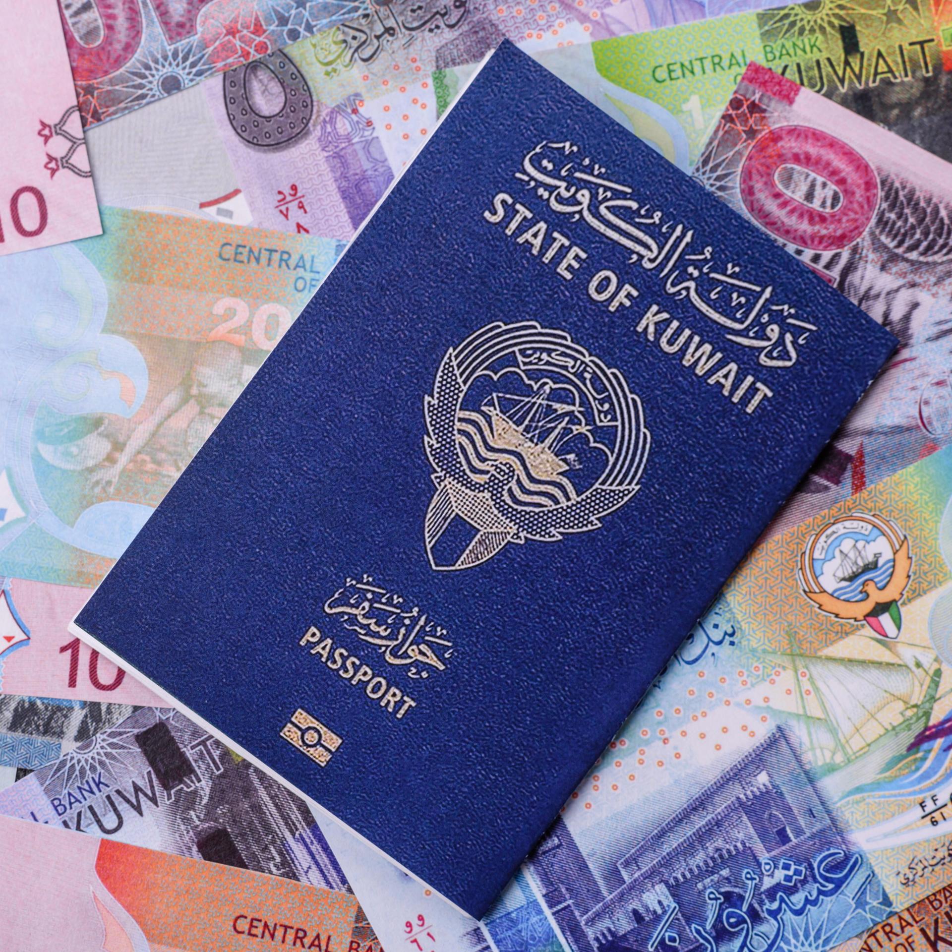 Ein kuwaitischer Reisepass für Reisen, Flugreisen und geschäftliche Zwecke liegt auf mehreren Geldscheinen. 